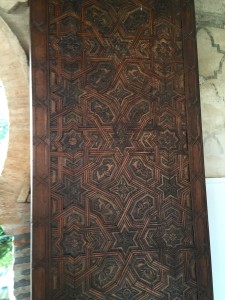 Hand carved door separating one of the patios from outside next to a horseshoe arch